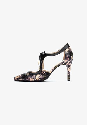 Zapato de tacón alto negro con punta afilada, lados con patrón floral y diseño de tiras en forma de T, que presenta material texturizado y acentos dorados.