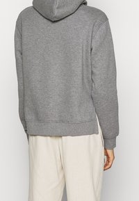 Felpa grigia in tessuto misto cotone, con un grande cappuccio, polsini e orlo a coste, e un fit rilassato con un design semplice.