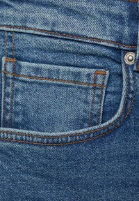 Denim tkanina plave nijanse, s džepom na zakrpi, kontrastnim narančastim šavovima i metalnim dugmetom kao dekoracijom na pojasu.
