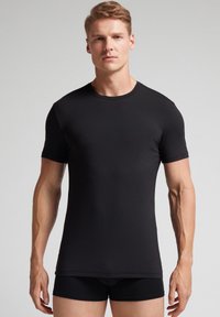 Camiseta negra de manga corta y cuello redondo, hecha de un tejido suave y ligero, con un diseño ajustado y construcción sin costuras.