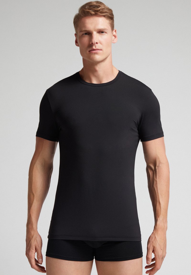 Camiseta negra de manga corta y cuello redondo, hecha de un tejido suave y ligero, con un diseño ajustado y construcción sin costuras.
