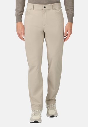 Chini beige con una trama liscia, design standard a cinque tasche e chiusura con bottone, abbinati a scarpe da ginnastica neutre.