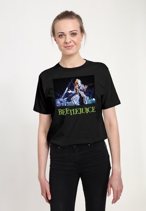Zwarte t-shirt met een grafische afbeelding van een personage in een gestreepte pak tegen een stormachtige achtergrond, met "BEETLEJUICE" in groene tekst eronder.