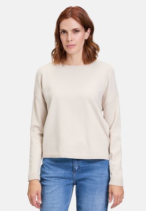 Pull beige clair, col rond, manches longues, bords côtes aux poignets et à l'ourlet, texture douce. Assorti avec un jean bleu. Design minimaliste.