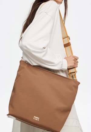 Bolso de hombro de tela marrón con una textura suave, que presenta una correa ancha con acentos amarillos y un detalle de logo en el borde inferior.
