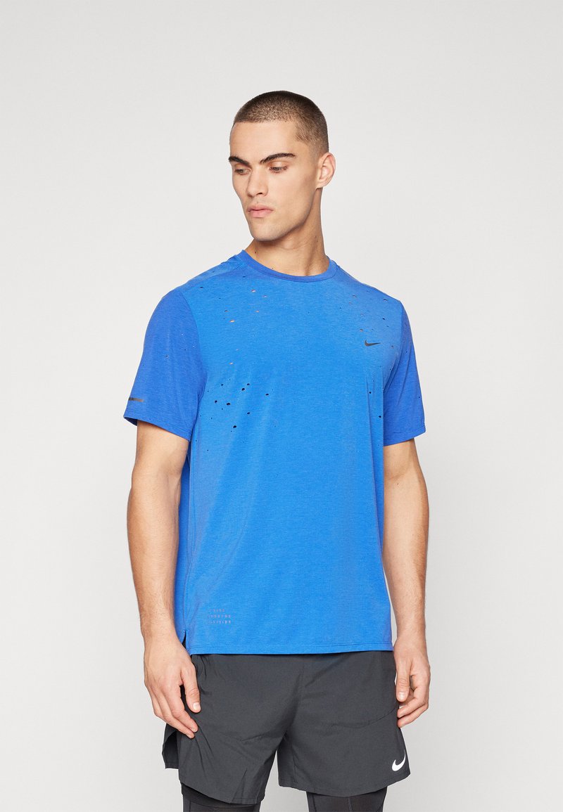 Sinine sportlik T-särk lühikeste varrukatega, millel on kulunud aktsendid ja must Nike logo rinnal. Pehme, hingav kangas.