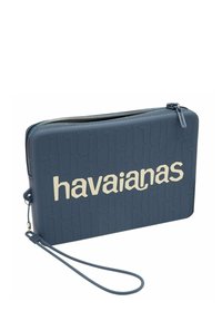 Borsa a pochette in silicone blu con logo "havaianas" in rilievo. Presenta una chiusura con zip e una cintura da polso per una facile maneggevolezza. Tessuto liscio.