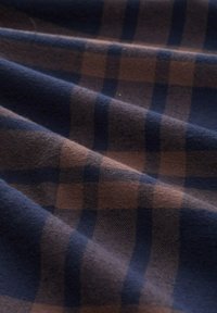 Geweven stof met een marineblauw en bruin ruitpatroon, gekenmerkt door prominente vierkantvormen, een zachte textuur en een subtiele glans.