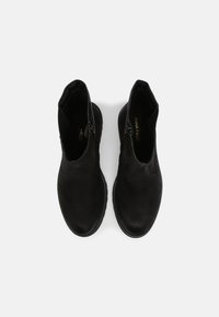 Botines negros de tobillo con una textura de cuero suave, que cuentan con un cierre de cremallera en el lateral y una puntera redondeada. Suela de goma con relieve para mayor agarre.