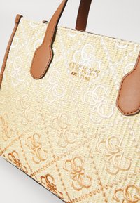 Straw handbag featuring a beige textured surface with embossed logo patterns and brown synthetic leather handles. Gold-tone logo detail.