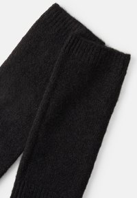Calentadores de piernas de lana negra con una textura suave, que cuentan con puños acanalados en la parte superior. El diseño es simple y sin costuras, ideal para mantener el calor.