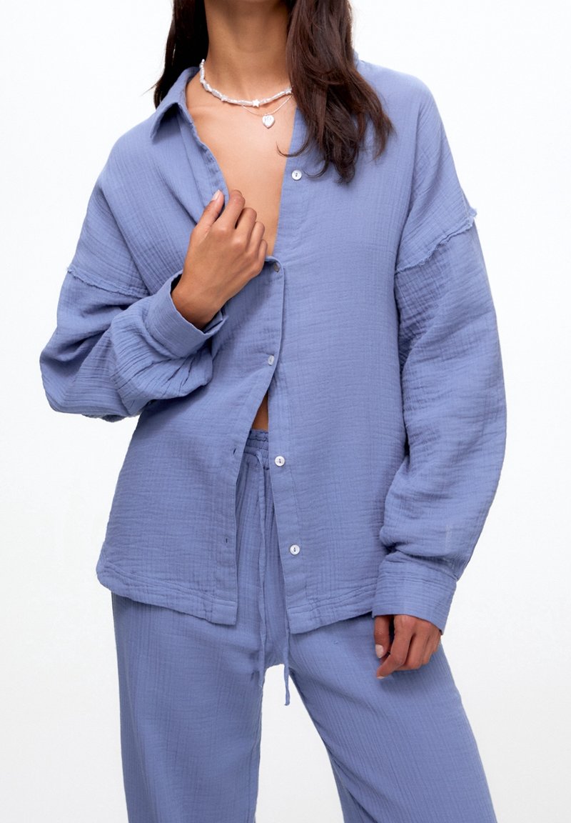 Ljusblå, långärmad skjorta med knappar i en strukturerad tyg, som har en avslappnad passform och lagerdesign med en något öppen krage.