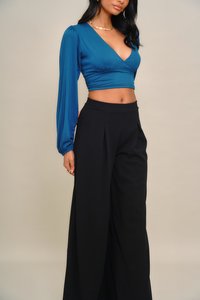 Türkizkék, rövidített felső hosszú, puffos ujjakkal és mély V-nyakkivágással, magas derekú fekete, bőszárú nadrággal párosítva. Simogató, finom anyag.