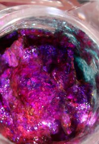 Glanzende gel-achtige cosmeticaproduct in een heldere container, met vibrerende paarse en blauwe tinten en iriserende sprankels verspreid over het geheel.