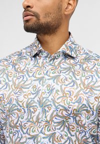 Camicia bianca con un vivace motivo paisley verde, blu e arancione, dotata di un colletto classico e chiusura con bottoni.