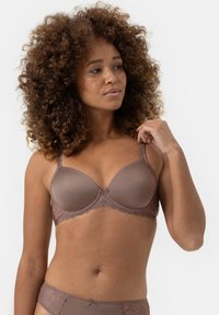 Formschalen-BH in gedämpftem Braun mit Spitzenbesatz und verstellbaren Trägern. Glatte Textur mit einem dezenten Schleifendetail in der Mitte.