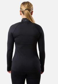 Maglietta atletica nera a maniche lunghe con un design aderente, texture liscia e colletto alto che presenta un motivo sottile.