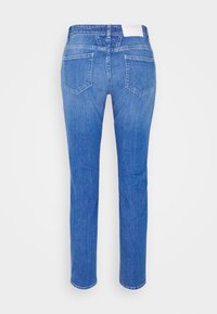 Blå denimjeans med rak benklipp, fem fickor och en ljus tvätt, med en vit etikett vid midjan och fållade kanter.