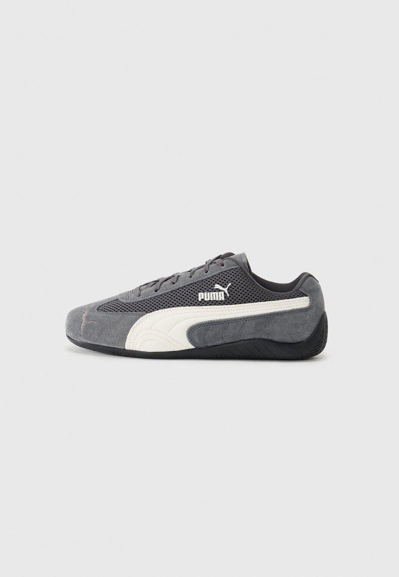 Baskets Puma grises profil bas avec bande latérale blanche, semelle noire, tige en mesh et suède, vues de côté extérieur sur fond gris.