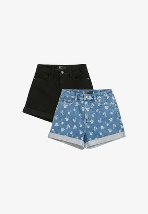 Două perechi de pantaloni scurți din denim, una neagră cu tivuri rulate, cealaltă albastră cu imprimeu floral alb și tivuri rulate, așezate pe o suprafață albă.