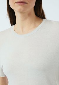 Hellgraues kurzärmeliges Shirt mit rundem Ausschnitt, gefertigt aus einem weichen, glatten Strickstoff. Verfügt über ein dezentes geripptes Kragen-Detail.