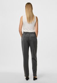 Graue maßgeschneiderte Hose mit einem lockeren Schnitt, ausgestattet mit einem dehnbaren Bund und zwei Gesäßtaschen. Glattes Gewebe mit dezenten vertikalen Streifen.