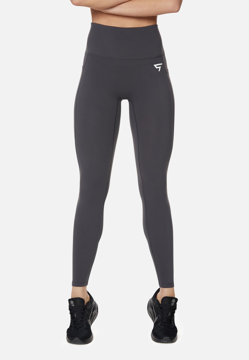 Hög midja grå leggings gjorda av elastiskt tyg med en slät känsla, med en logotyp på vänster sida och en åtsittande design.