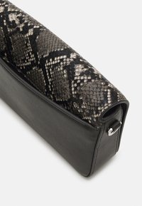 Mustalla nahkaperustalla varustettu clutch-laukku, yläosa harmaassa ja mustassa käärmekuvioidussa tekstuurissa. Laukussa on yksinkertainen muotoilu ja hopeanväriset metalliosat.