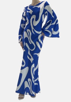 Mannequin portant une longue robe bleue avec des tourbillons blancs abstraits, une manche évasée et des talons blancs ouverts à l'avant, posant avec la main sur la hanche.