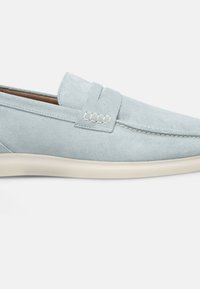 Lichtblauwe suède instappers met een ronde neus, gestikte accenten en een crèmekleurige rubberen zool. Klassiek slip-on ontwerp zonder zichtbare hardware.