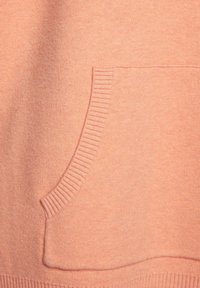 Pfirsichfarbener Pullover aus weichem Material, mit einer gerippten Tasche und Säume, der ein schlichtes und glattes Design zeigt.