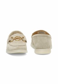 Zapatos de ante beige sin cordones con un detalle de cadena dorada, punta redondeada y suela de goma suave. Textura lisa con detalles de costura mínimos.