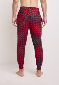 Rode geruite pyjamabroek met een zwart en blauwe ruitenpatroon, elastische tailleband, taps toelopende benen en enkelmanchetten. Zacht materiaal.