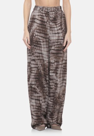 Pantaloni a vita alta a gamba larga con motivo astratto di pelle di rettile marrone e grigia, indossati con scarpe taupe con punta appuntita.