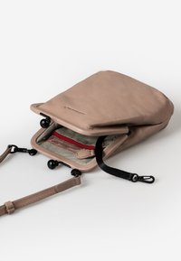 Borsa a tracolla in pelle tan con chiusura a zip, foderata internamente con tessuto a righe e dotata di una tasca rossa con zip. Presenta una tracolla regolabile e dettagli in metallo.