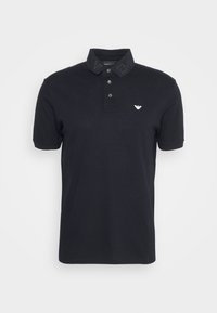 Svart pikétröja i bomull med en texturerad krage som har "EA"-tryck, två knappar och en liten logotyp på bröstet.