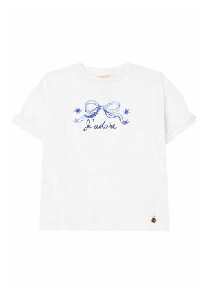 T-shirt blanc à manches courtes avec un nœud à pois bleu, deux petites fleurs, texte "J’adore" en bleu, et une petite coccinelle près de l'ourlet inférieur.