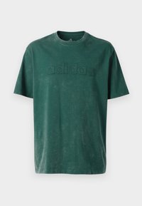 Tmavohnedé bavlnené tričko s okrúhlym výstrihom, krátkymi rukávmi a embosovaným logom "adidas" na hrudi v rovnakom prevedení.