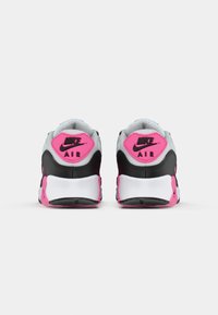 Balta, juoda ir ryškiai rožinė spalvų Nike Air sportbačių pora, matoma iš nugaros ant vienspalvio balto fono.