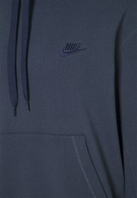 Navyblauwe Nike hoodie gemaakt van zachte stof, voorzien van een voorzak, trekkoorden en een klein geborduurd logo op de borst.