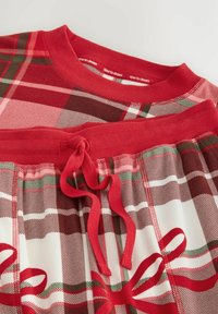 Red plaid pajama set featuring a ribbed crew neckline and tie waist. Material is soft with a smooth texture and decorative bow patterns in red.
