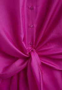 Fuchsia blouse met een knoopsluiting aan de voorkant, voorzien van een gestrikte knoopdetail in de taille, gemaakt van lichtgewicht, gladde stof, en een effen kleur.