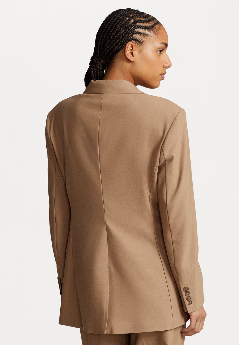 Brauner maßgeschneiderter Blazer mit Reverskragen, strukturierten Schultern, Rückenbelüftung und geknöpften Manschetten sowie feiner Textur.