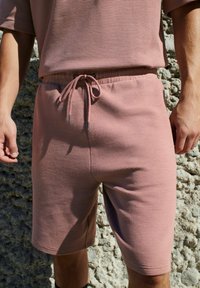 Lyserøde ribbede shorts med elastisk talje, justerbar snor og en afslappet pasform med sidelommer.