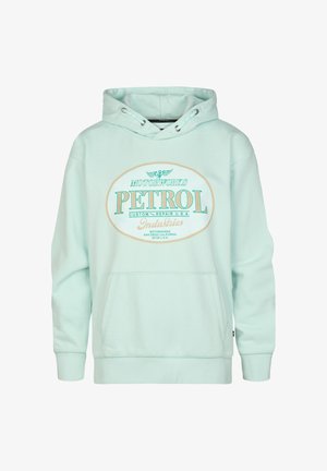 Hellblauer Hoodie mit Frontgrafik, ausgestattet mit einer Kängurutasche, kombiniert mit verblassten blauen Jeans und weißen Sneakers. Schlichtes Design, lässige Passform.