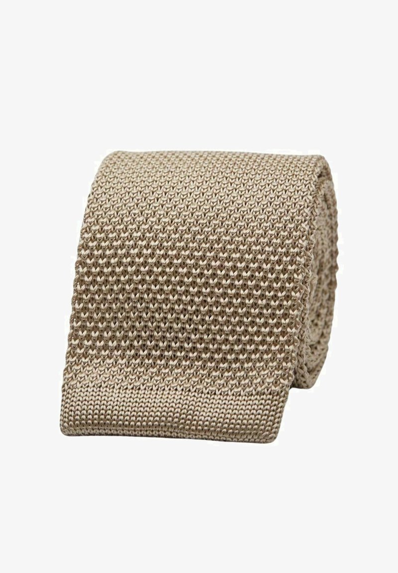 Beige punottu vyö, jossa on tekstuuri ja uritettu kuvio. Materiaali on pehmeä ja joustava, rullattu siististi esillepanoksi.