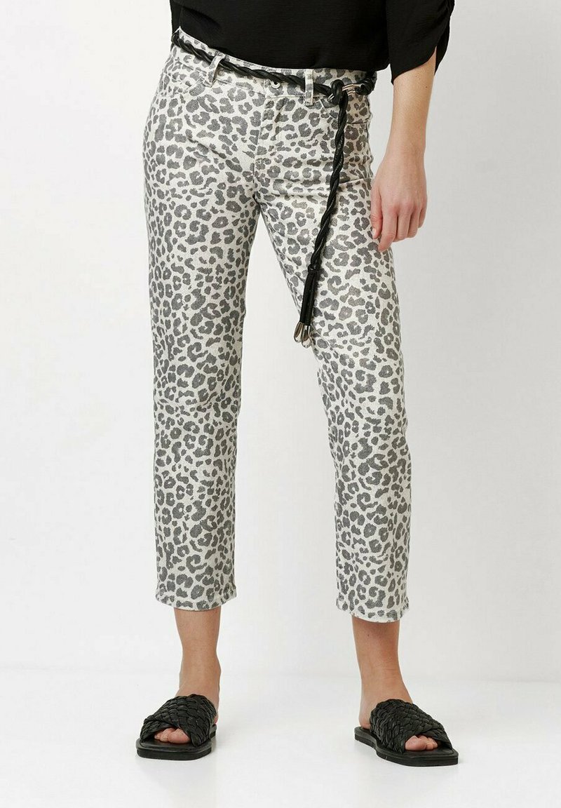 Grau leopardgemusterte Hose auf hellem Hintergrund, mit einem schwarzen Gürtel, verkürztem Bein und kombiniert mit schwarzen, gewebten Rutschen-Sandalen.