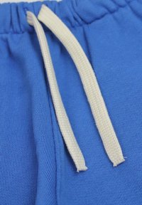 Shorts en coton bleu avec une texture côtelée et une taille élastique, dotés d'un cordon blanc partiellement tiré à l'avant.