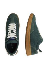 Zapatillas de ante verde con un upper texturizado, cordones blancos y una suela de goma. Presentan un collar acolchado y un branding sutil en la lengüeta.