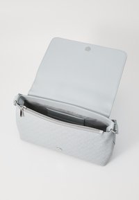 Gray patterned handbag with a smooth, light gray interior. Features a zippered pocket and a snap closure, designed with subtle hardware details.